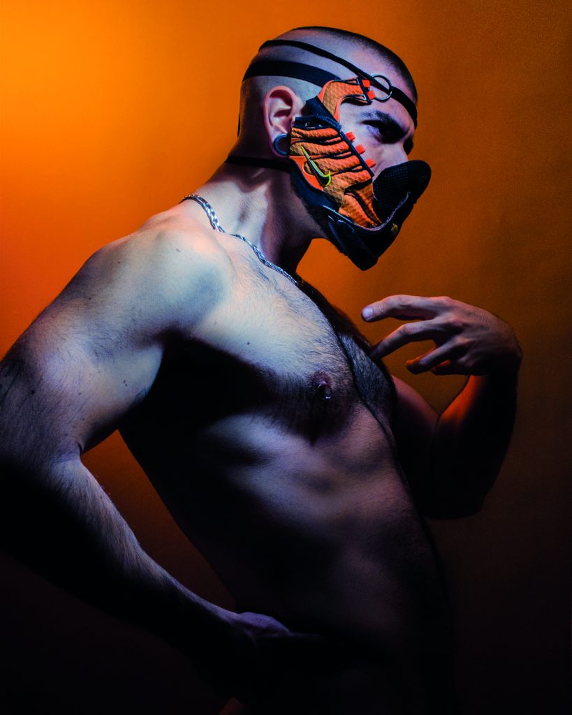 L'artiste Albinohector torse nu qui porte un masque de sa fabrication