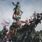 Des militants arborent fièrement leurs drapeaux trans et LGBT sur la statue de la place de la République, à Paris.