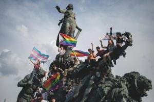Des militants arborent fièrement leurs drapeaux trans et LGBT sur la statue de la place de la République, à Paris.